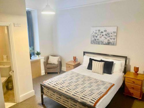 a bedroom with a large bed and a chair at Bright 2 Bedroom Apartment near Seafront Central Penzance in Penzance