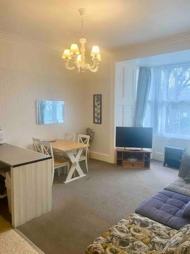 a living room with a table and a television at Bright 2 Bedroom Apartment near Seafront Central Penzance in Penzance