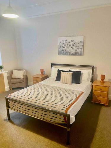 a bedroom with a large bed and a chair at Bright 2 Bedroom Apartment near Seafront Central Penzance in Penzance