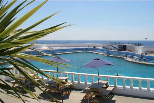 a large swimming pool with chairs and an umbrella at Bright 2 Bedroom Apartment near Seafront Central Penzance in Penzance