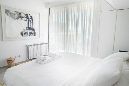 a white bedroom with a white bed and a window at Zita Fidar in Al Fīdār