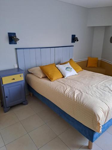 1 cama con almohadas amarillas y mesita de noche azul en Appart 2 personnes proche plage de la Fresnaye, en Saint-Cast-le-Guildo