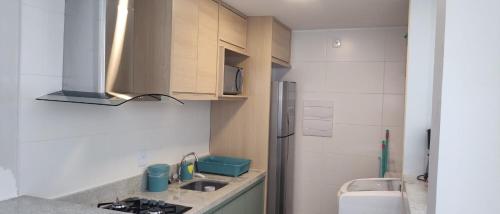 a small kitchen with a sink and a refrigerator at Itacimirim Apartments Boulevard e Ondas in Itacimirim