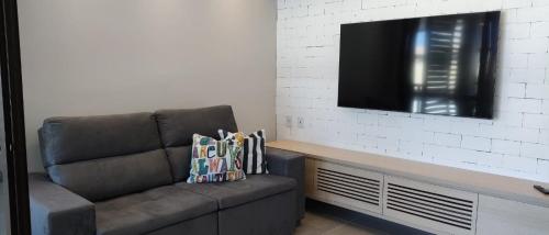 a living room with a couch and a flat screen tv at Itacimirim Apartments Boulevard e Ondas in Itacimirim