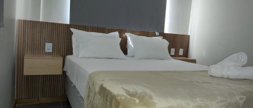 a bedroom with a large bed with white sheets and pillows at Itacimirim Apartments Boulevard e Ondas in Itacimirim