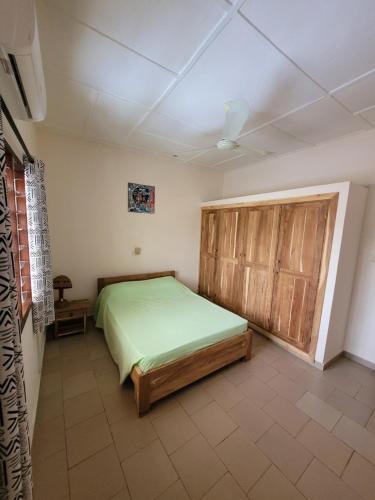 a bedroom with a bed and a wooden door at La Belle Vie Là de Ouidah in Ouidah