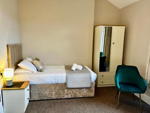 a bedroom with a bed and a green chair at Hotel No5, Beachfront with Free Private Car Park in Llandudno