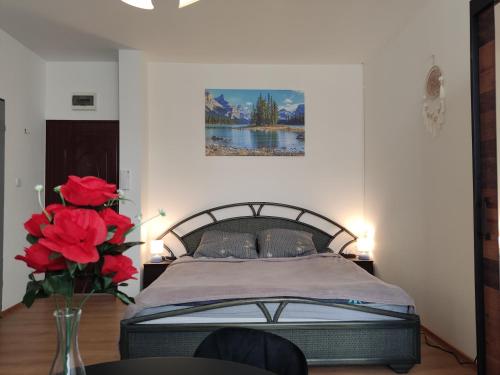 a bedroom with a bed and a vase with red roses at Mini Apartament Studio in Głuchołazy
