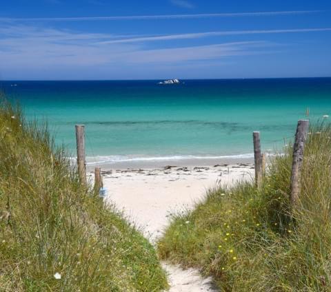 a sandy beach with a fence and the ocean at Ker Melen in Cléder