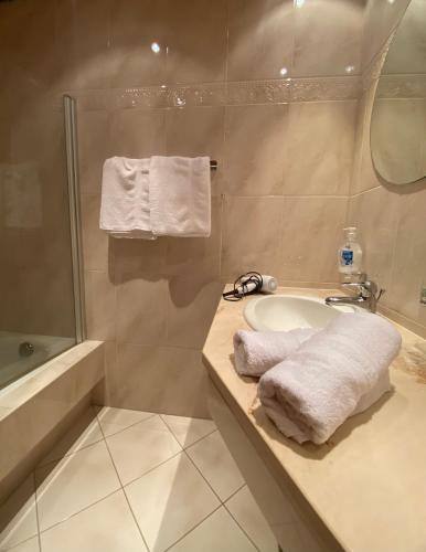 a bathroom with a sink and a shower with towels at Landhaus Rosengartl Krimml in Oberkrimml