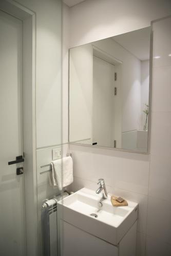 a white bathroom with a sink and a mirror at Zita Fidar in Al Fīdār