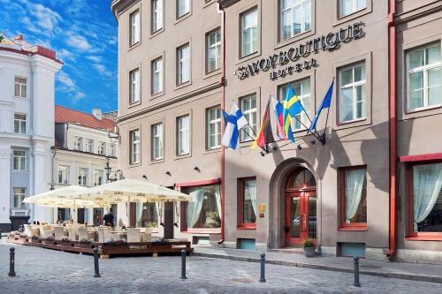 ein Gebäude mit Tischen und Sonnenschirmen davor in der Unterkunft Rixwell Collection Savoy Boutique Hotel in Tallinn