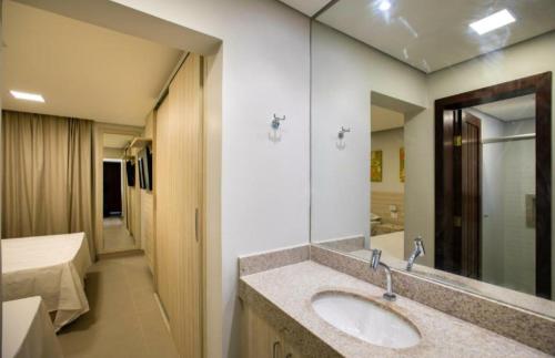 baño con lavabo, cama y espejo en Hotel Encantos de Itaperapuã, en Porto Seguro