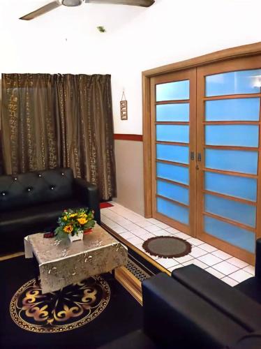 a living room with a black couch and a table at Bidadari Lagoon 4 Islamic Homestay in Port Dickson
