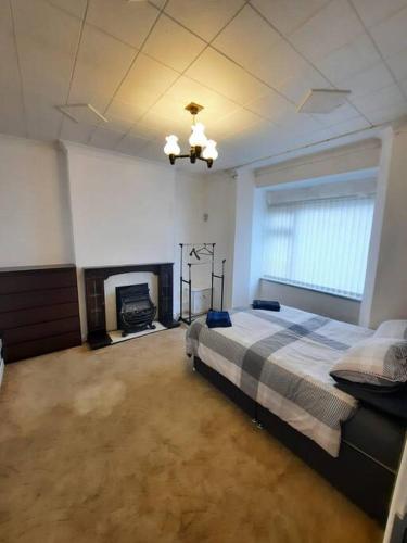 een grote slaapkamer met een bed en een open haard bij Basic 5-bedroom home - Affordable accommodation for groups in Swansea