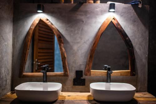 two sinks in a bathroom with two windows at Baobab Bungalows in Jambiani