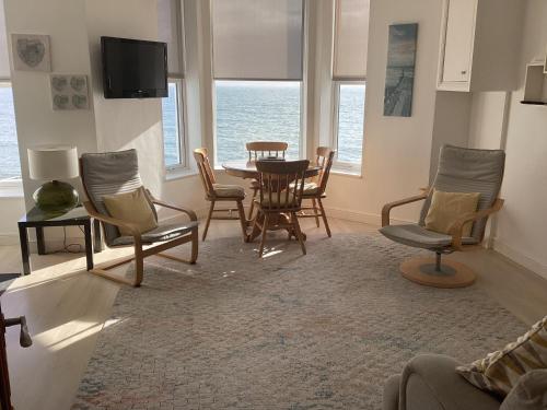 uma sala de estar com mesa e cadeiras em Marine Terrace Apartments em Criccieth