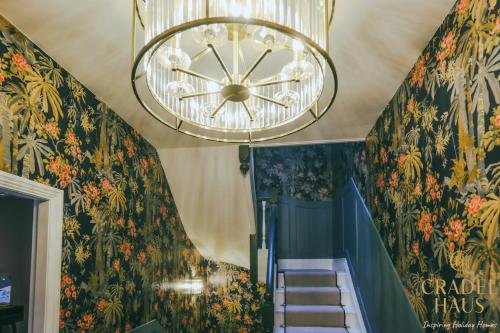 a chandelier hanging over a staircase with floral wallpaper at Fair Rigg by Cradel Haus - Ultra Luxury Lakes Holiday Homes, Pet Friendly, Parking & EV Plug in Bowness-on-Windermere