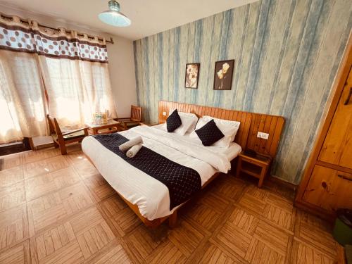 Hotel Kanchani - A Majestic Mountain Retreat في مانالي: غرفة نوم بسرير كبير عليها شراشف ووسائد بيضاء