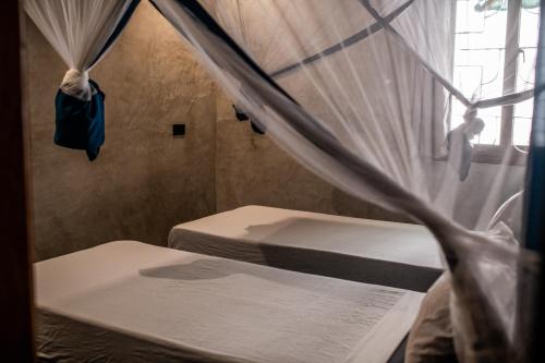 two beds in a room with a window at Baobab Bungalows in Jambiani
