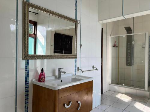 y baño con lavabo, espejo y ducha. en TR GUEST HOUSE en Matola