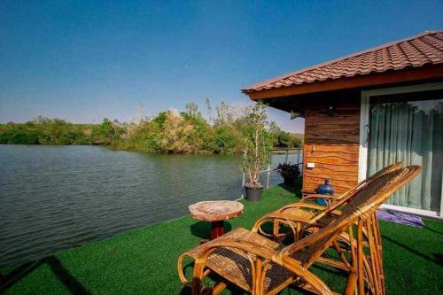un patio con 2 sillas y una mesa junto a un lago en บ้านกลางโดม Baan Klang Dome, 