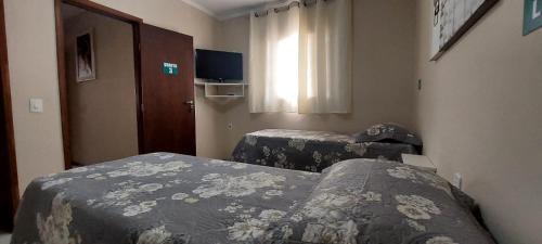 a hotel room with two beds and a window at Pousada Palmeira in Viracopos