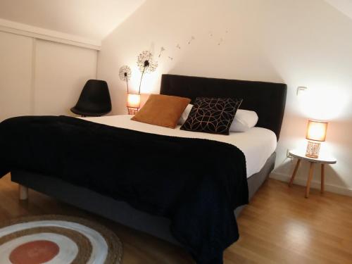 a bedroom with a large bed with black sheets and pillows at Le Duplex, parking wifi aux portes de vannes in Vannes