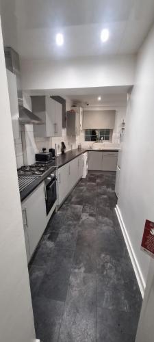 a large kitchen with white cabinets and appliances at The Manor Guest House in Wembley in London