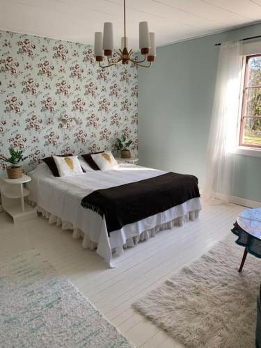 1 dormitorio con 1 cama en una habitación con papel pintado con motivos florales en Lantligt boende nära Kastelholms golf och Smakbyn, 