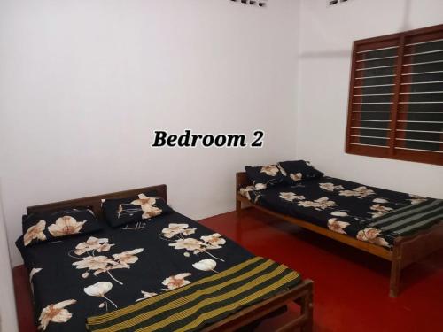 two beds in a room with the words bedroom two at Kilner Lane Guest House in Jaffna