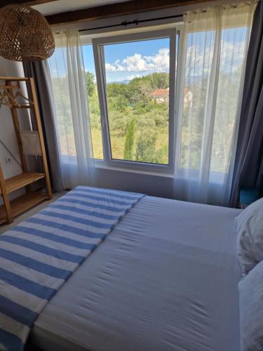 łóżko w pokoju z dużym oknem w obiekcie Apartment Buric w mieście Županje