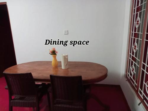 a dining room table with chairs and a vase of flowers at Kilner Lane Guest House in Jaffna