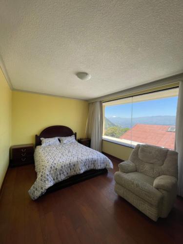 a bedroom with a bed and a chair and a large window at Oportunidad González Suárez, Quito in Quito