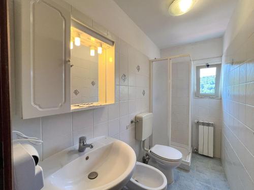 a white bathroom with a sink and a toilet at Mandel Club in Capoliveri