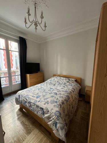 une chambre avec un lit et un lustre dans l'établissement Grand appartement Michel-Ange, à Paris