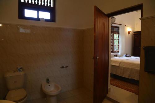 a bathroom with a toilet and a sink and a bed at InVilla Hikkaduwa Sri Lanka in Hikkaduwa