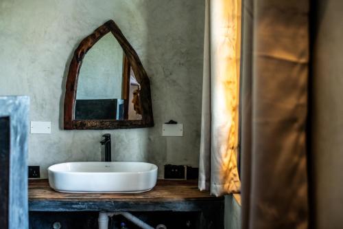a bathroom with a white sink and a mirror at Baobab Bungalows in Jambiani