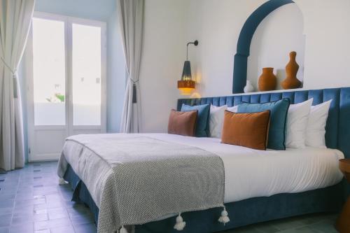 um quarto com uma cama azul e branca com almofadas em Le Palazzo em Essaouira