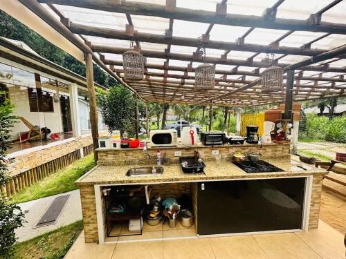 una cocina al aire libre con pérgola y barra en Camping Mill Off Adventure, en Paraty