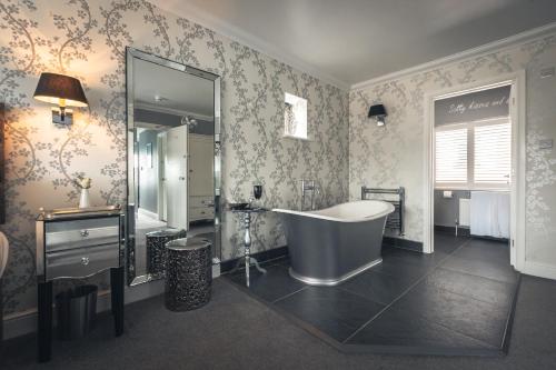 uma casa de banho com uma banheira, um lavatório e um espelho. em Driftwood B&B em Brixham