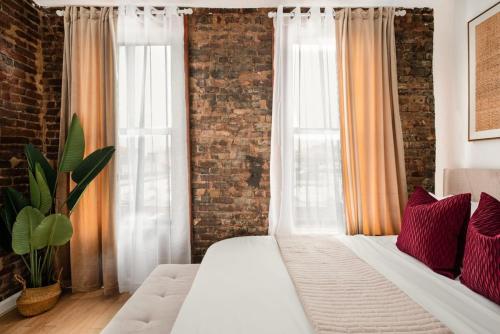 ニューヨークにある153-5A Charming 2BR LES W Dの白いベッドとレンガの壁が備わるベッドルーム1室が備わります。