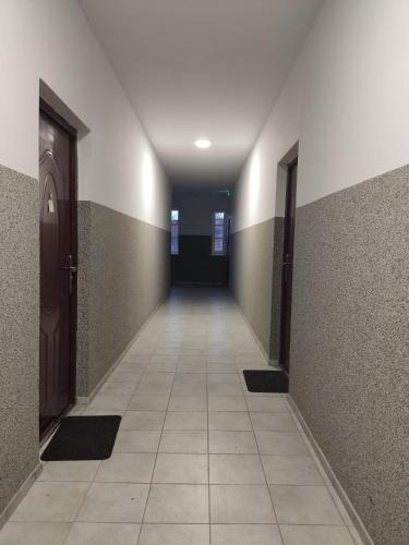 pusty korytarz z drzwiami i podłogą wyłożoną kafelkami w obiekcie Mini Apartament Studio w mieście Głuchołazy