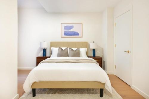 a bedroom with a large white bed with two lamps at 76-1D Brand New 4BR 3BTH UES Doorman Gym in New York