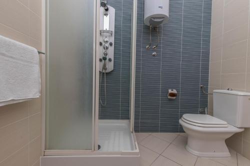 a bathroom with a toilet and a shower with blue tiles at Simba Apartman 59 in Selce