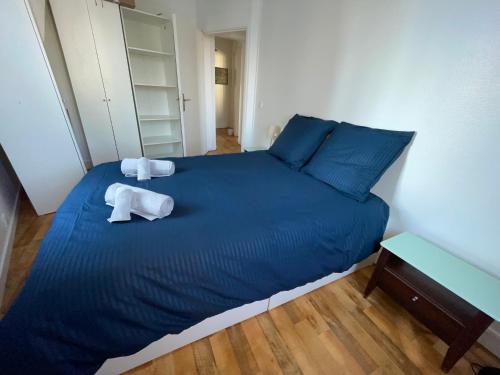 une chambre avec un lit bleu avec deux serviettes dessus dans l'établissement 3P cosy et lumineux proche de La Défense et Paris, à La Garenne-Colombes