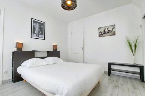 a white bedroom with a large bed and a table at Charmante maison de ville centre historique Tours 5p in Tours