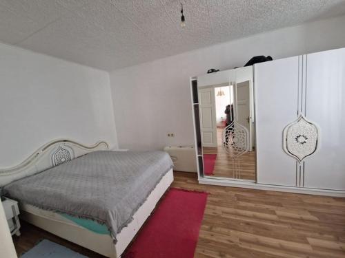 a white bedroom with a bed and a mirror at Modern und Gemütlich in Ebenfurth