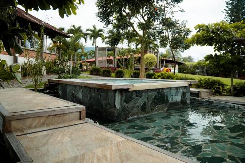a pool in the middle of a yard with trees and a house at Finca Hotel Yerbabuena in Pereira