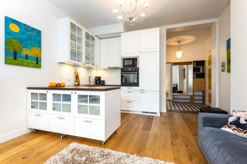 a kitchen with white cabinets and a blue couch at Cozy home in the city center- contactless self check in in Tallinn